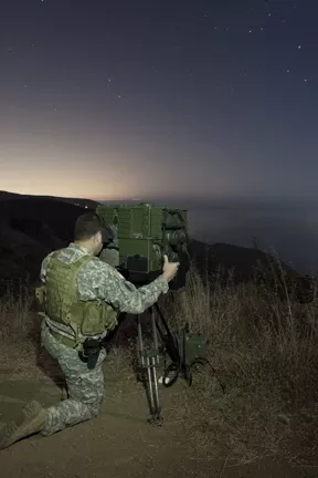 EYES ON THE WATER : A National Guard soldier peers through a LRAS-3 long-range night vision scope to scan the horizon for suspicious watercraft. The U.S. National Guard’s counter-drug coastal surveillance team took New Times for a ride-along atop the hills overlooking the Ventura County coastline. - PHOTOS BY STEVE E. MILLER