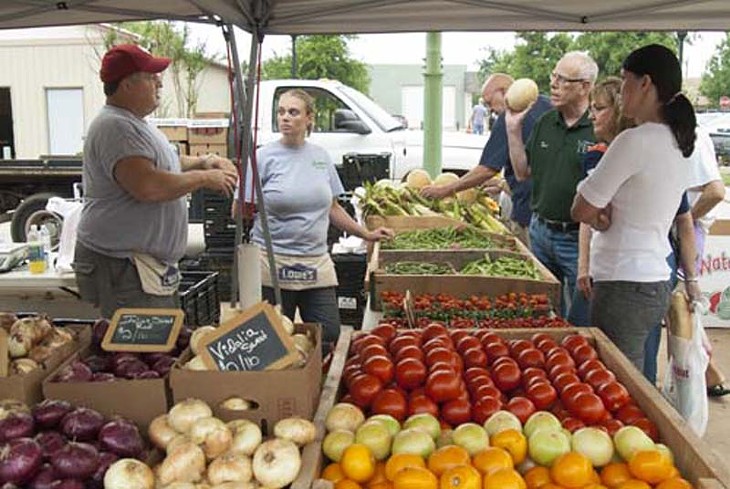 Greg Loman of Loman's Landscape Design and Garden Center, left, discusses produce with customers, next to Loman's Melissa Abbey, Saturday Morning, 5-31-14, at the Edmond Market.  mh