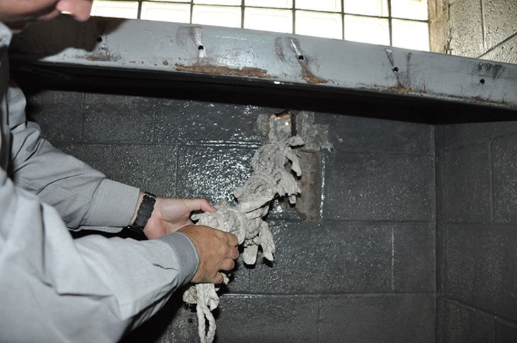 An Oklahoma County Sheriff's Department investigator removes a jail-made rope from a hole in an eighth-floor cell. Investigators believe inmates used the hole to store rope and other contraband in preparation for an escape attempt. (Oklahoma County Sheriff's Office / Provided)