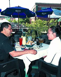 Left, Ruben Fuentes with Laura Gomez, pose at a table setting on the patio at the Bricktown Chelino's. mh both are employees with Ruben being the GM.