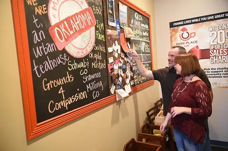 Perk Place Cafe owners Natalie and Jeff Meyer, look over charity donations, Make in Oklahma connections, and biz card bulletin board. mh