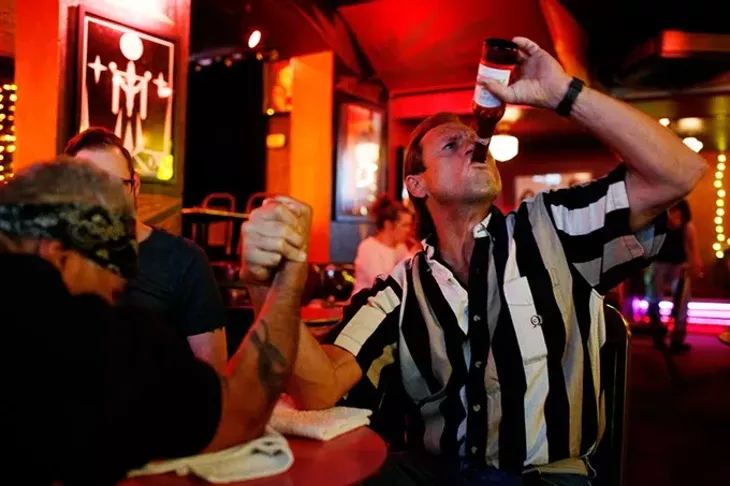 Mark Hughes takes a drink of his beer as he arm wrestles Al Rojas Jr. at the Hilo Club in Oklahoma City, Friday, Nov. 6, 2015. - GARETT FISBECK