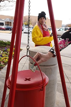 A woman donates a few dollars at the Salvation Army collection kettle, manned by Gladys Brady, a paid bell ringer, near an entrance to Penn Square Mall. - MARK HANCOCK