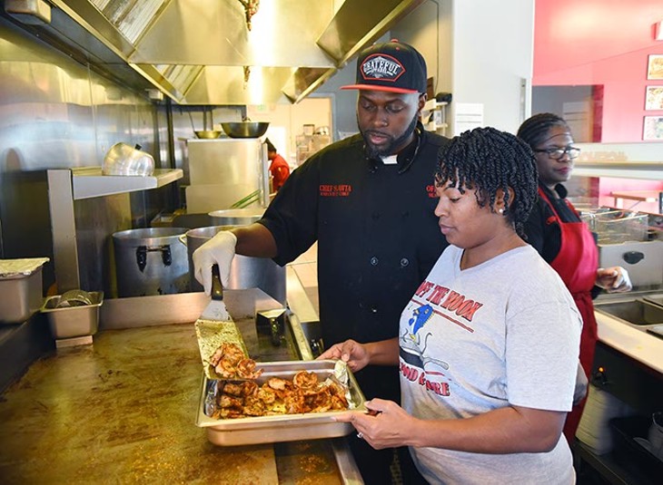 Loniesha and Corey Harris take some shrimp off the grill in the preparation of their popular seafood grits in their new brick-and-mortar location at 125 W. Britton Road. (Mark Hancock)
