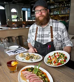 Exec. Chef Chris McKenna at Packard's presents a kale chopped salad with gorganzola bleu cheese, red onion, chick peas, peppidu peppers, and a golden basalmic dressing. On one plate is Rockinville Oysters behind the Autumn obile cocktail made with rye whiskey, Cinnamon Apple Shrub, Ango Bitters and Tawny Port float. For the main dish, Duck with bacon and brussels, butternut squash puree with hard cider dressing. (Shannon Cornman)
