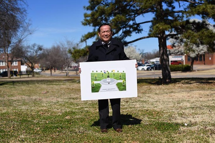 Vinh Nguyen poses for a photo with a picture of a American Community Vietnam Monument at Military Park in Oklahoma City. - GARETT FISBECK