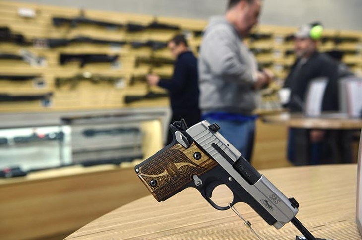 Shoppers can handle the pistols attached to convenient display tables at the new Wilshire Gun Range, photographed during grand opening, 11-14-14.  mh