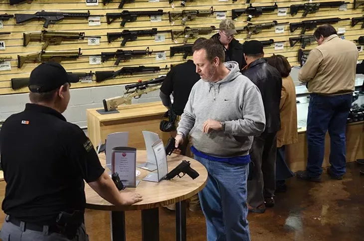 Shoppers can handle the pistols attached to convenient display tables at the new Wilshire Gun Range, photographed during grand opening, 11-14-14. mh
