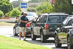 A man folds up his cardboard sign that reads "Homeless And Hungry Please Help Anything", and excepts a cash hand-out from a motorist waiting to turn at the light at the intersection of N.W. Expressway and Belle Isle Boulevard, 9-17-15. - MARK HANCOCK