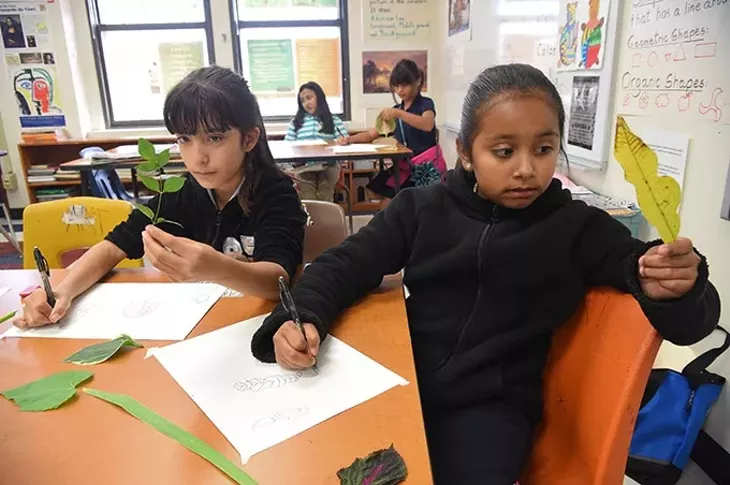 Left to right, Jackie Carrera and Emili Carrion, both 4th graders at Lee Elementary School in OKC, study their own leaves and transfer what they see to the paper as they participate in an after school art project at the Southside OKC School, 9-14-15. - MARK HANCOCK