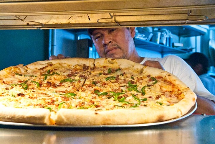 Jorge Resendiz places a large combo pizza in the pizza by the slice rack, at Empire Slice House.  mh