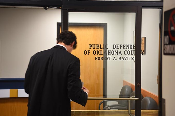 An attorney waits looks over his paperwork befere entering the Public Defender of Oklahoma County offices, 9-24-15. - MARK HANCOCK
