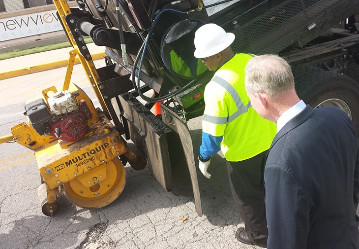 Mayor Mick Cornett watches as a city workers repairs a pothole that was reported using the city's new mobile app. - BEN FELDER