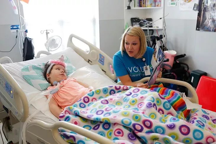 Trisha McVicker reads to Abby Gonzales as part of the Volume Summer Program at The Children's Center in BethanyTuesday, June 14, 2016. - GARETT FISBECK
