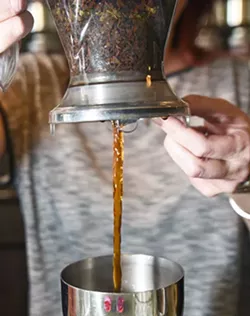 Kristy Jennings, owner of t an Urban Teahouse, pours the hot tea into the first cooling container filled with Ice. mh