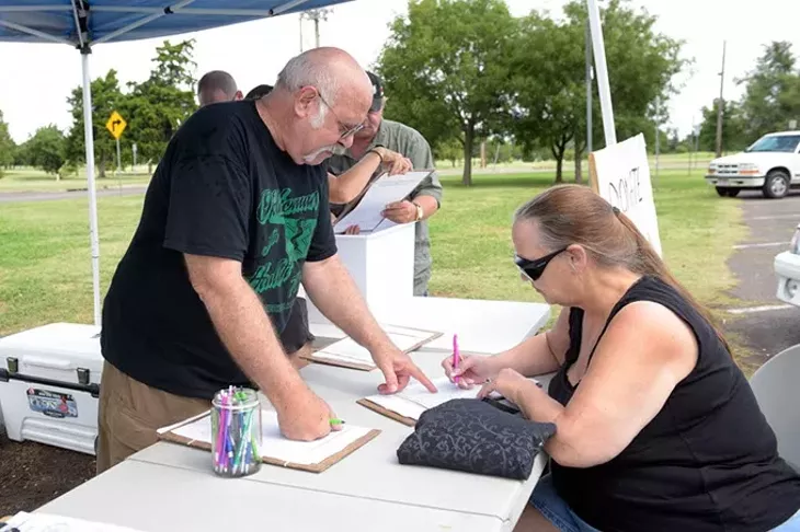 Clinton Wiles assists Randi Thacker during a petition signing put on by Oklahomans for Health, Tuesday, July 26, 2016. - GARETT FISBECK