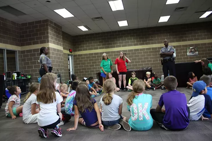 Sgt. Sherrica Buckingham left - and MSgt. Justin Echols listen as summer day - campers ask about the role of officers during - camp at Earlywine Park YMCA. | Photo Laura Eastes