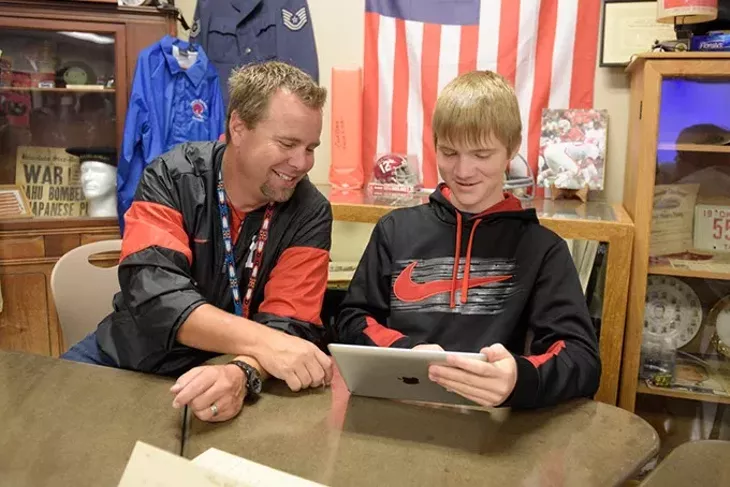 Rob Davis works with Erik Sproul in his classroom at Yukon High School. | Photo Garett Fisbeck