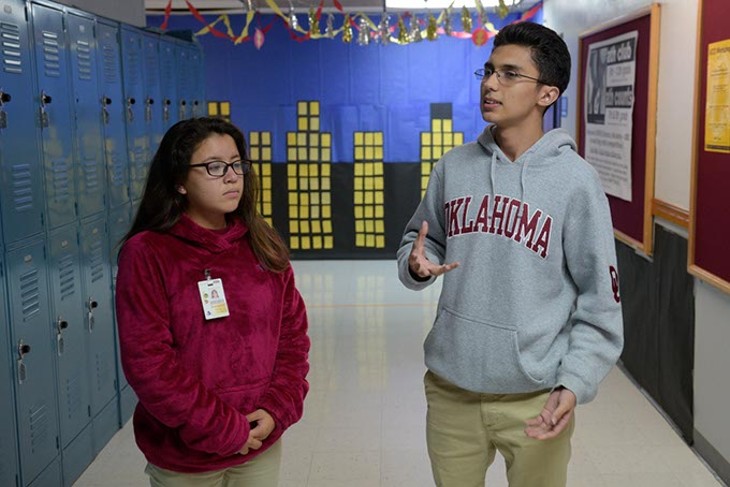 Senior Omar Camacho right explains how local college students visit Dove Science Academy OKC on Thursdays to mentor and help students like himself and Damaris Palma left with science homework. (Photo Garett Fisbeck)