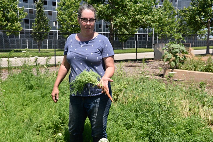 Gardener Jenn Mabry shows off a freshly harvested carrot from TLC Donation Garden. - JACOB THREADGILL