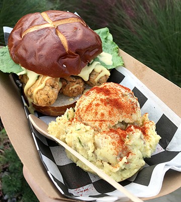 Seitan-based fried chicken is topped with honey mustard, pickles lettuce and served on a pretzel roll. - JACOB THREADGILL