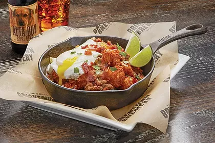 Green chili pork Totchos are topped with cheese, bacon and an egg. - PROVIDED