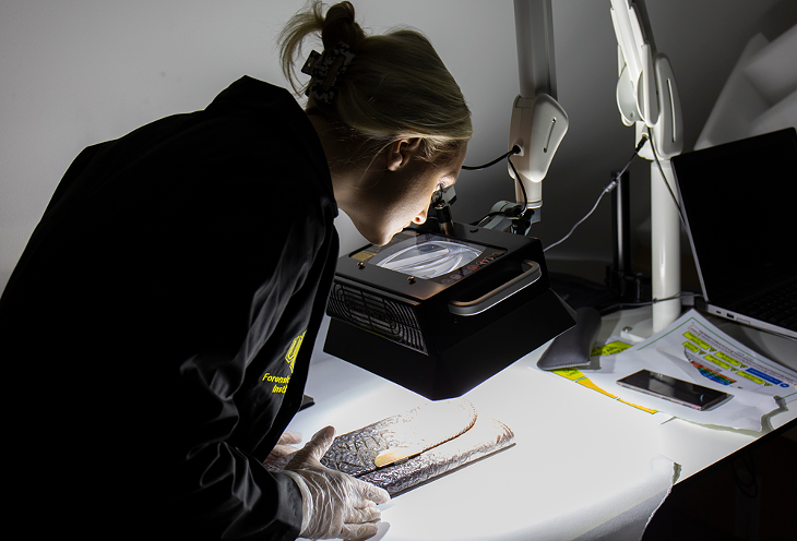 Hannah Walcher examines residue on the purse using an alternate light source. - BERLIN GREEN