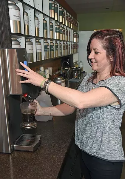 Kristy Jennings dispenses hot water into the black currant tea leaves during the iced tea making process. mh
