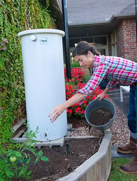 Jamie Csizmadia sprinkles some top soil over garden mulch next to a rain barrell at an Oklahoma City home. (Shannon Cornman)
