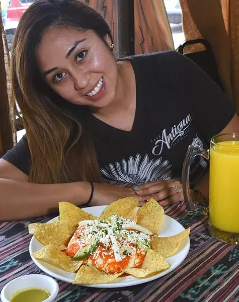 Cafe Antigua's Ana Sofia Del Cid, poses with vegitarian Huevos Motuleno double stack, with a fresh mango smoothy. mh
