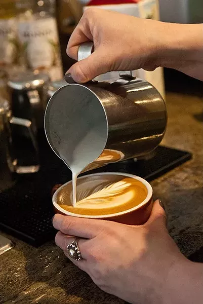 steamed milk is poured in the making of a latte by barista Tori Goben, at Coffee Slingers Roasters. mh