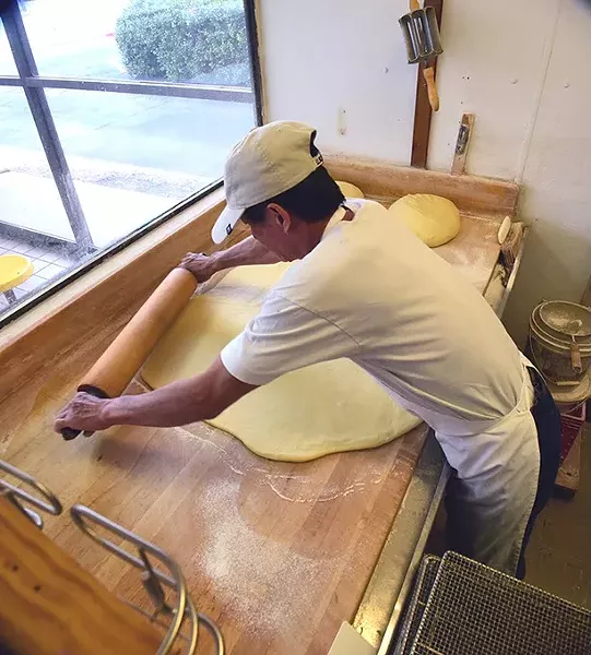 Sok San has been the baker at North May Donuts & Kolaches for over 5 years, shown rolling out kolache dough on the recent busy Christmas Eve morning. mh