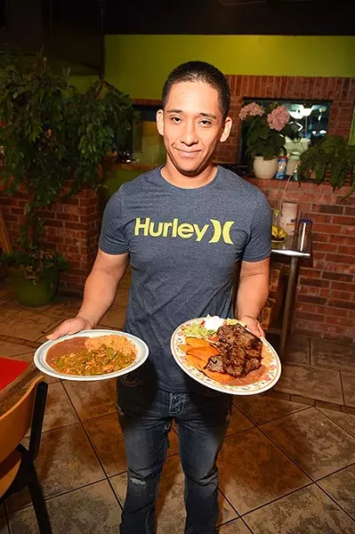 Son of owner, Oscar Zapata with Guisada de Puerco Verde con nopales, left, and Enchiladas Potosinas, at El Potosino restaurant, 2500 S. Robinson Avenue. mh