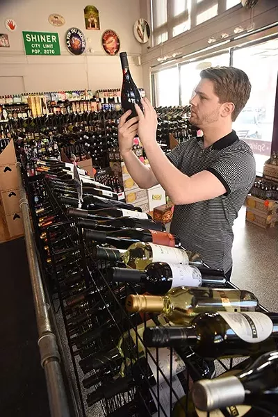 Employee Adam Rott reads a wine label at Broadway Wine Merchants in Auto Alley. mh