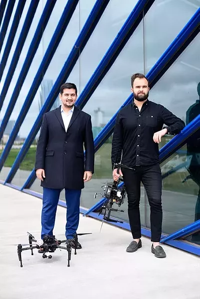 Ersin Demirci and Nick Brown pose for a photo with drones at the Boathouse District, Monday, April 11, 2016. - GARETT FISBECK