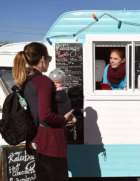 Customers Molly, left, and Samantha Cooper, order some hot chocolate at the Katiebut's camper, from Autumn Urton, left, and Jen Bellah, at the Holiday Pop-Up Shops in Midtown, 12-18-15, Oklahoma City. - MARK HANCOCK