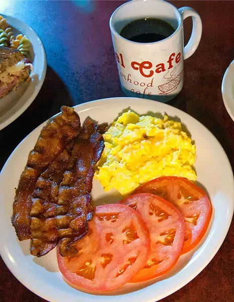 A tradition breakfast of eggs, bacon, but with tomato slices, along with some biscuits and a blueberry muffin and coffee. mh