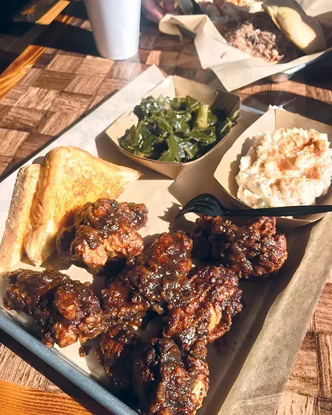 Fried chicken wings covered in jerk sauce with potato salad and greens at Cornish Smokehouse - JACOB THREADGILL