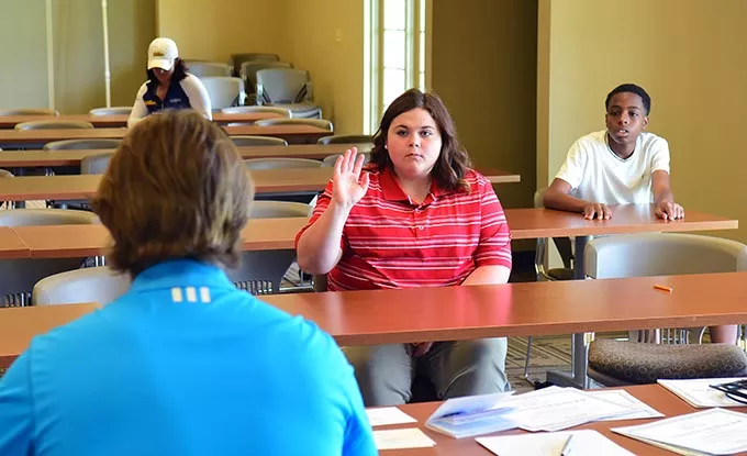Kirstin Westlake raisers her hand to answer a question during a short classroom session with director Dustin Semsch and others in her age group before the young golfers hit the course on a recent Saturday. mh