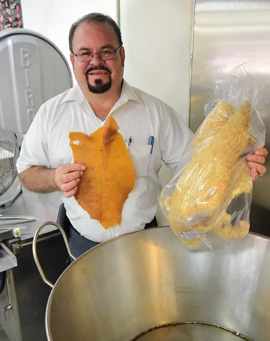 Marcelino "Chelino" Garcia himself shows the unfried and the finished fried Pork Rinds in a bag over the vat they are fied in, at Chelino's Meat Market, 2101 S. Robinson Avenue, 9-4-15. - MARK HANCOCK