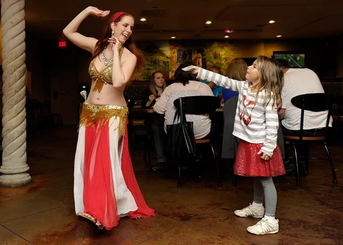 Theda Borja Lothrop, 6, tips Sevi Amar as she dances at Zorba's in Oklahoma City, Nov. 22, 2014. - GARETT FISBECK