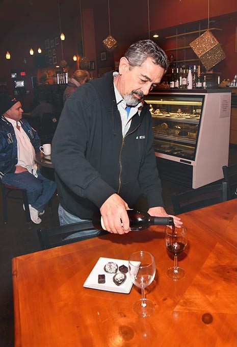 Michael Palermo, owner, pours Wine next to a selection of chocolate, the makings for a romantic get together, at Michaelangelo's Coffee and Wine in Norman, 1-21-16. - MARK HANCOCK