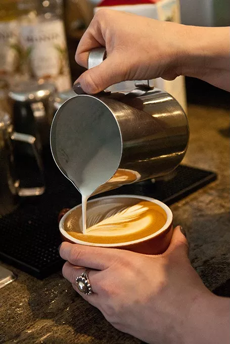steamed milk is poured in the making of a latte by barista Tori Goben, at Coffee Slingers Roasters. mh