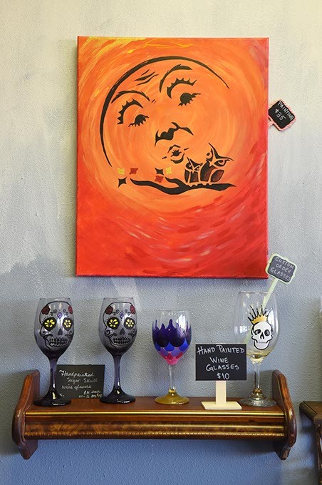 A painting overlooks hand painted wine glasses, at On the Edge with Skulls & Stones, at On the Edge with Skulls & Stones, in their new location in west OKC, 11-11-15. - MARK HANCOCK