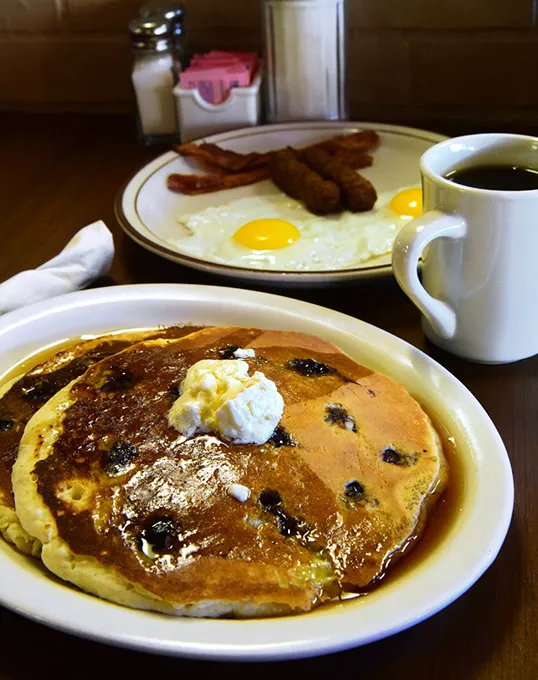 Breakfast with 2 eggs, bacon and Sasage, featuring a short stack of blueberry pancakes, at Woodbridge restaurant. mh