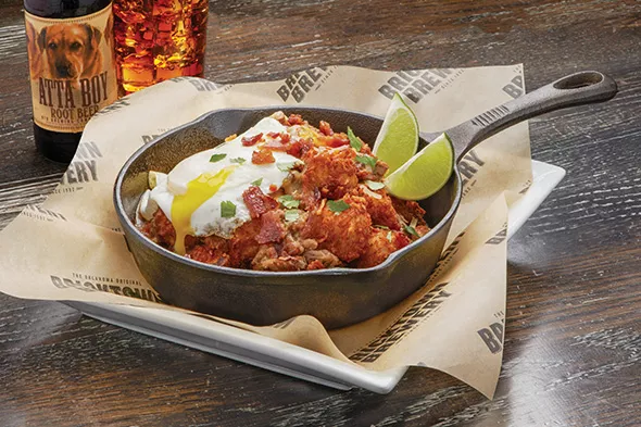 Green chili pork Totchos are topped with cheese, bacon and an egg. - PROVIDED