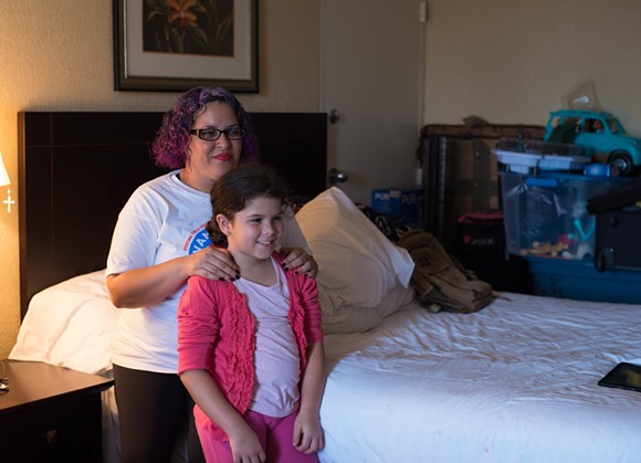 Bethzaida Crespo and her daughter sit near their packed belongings. - PHOTO BY MONIVETTE CORDEIRO