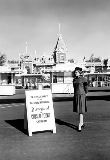 A cast member stands by a sign informing guests the Disneyland park is closed for the National Day of Mourning following President Kennedy's assassination - IMAGE VIA DISNEY/DISNEY.COM