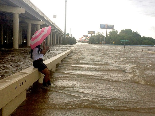 An umbrella didn’t furnish a lot of protection Sunday morning at Yale and Interstate 10. - PHOTO BY MEAGAN FLYNN