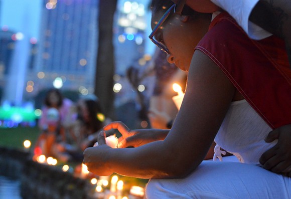A woman lights a candle at a small vigil for victims of the mass shooting at Pulse nightclub in Orlando. - PHOTO BY MONIVETTE CORDEIRO